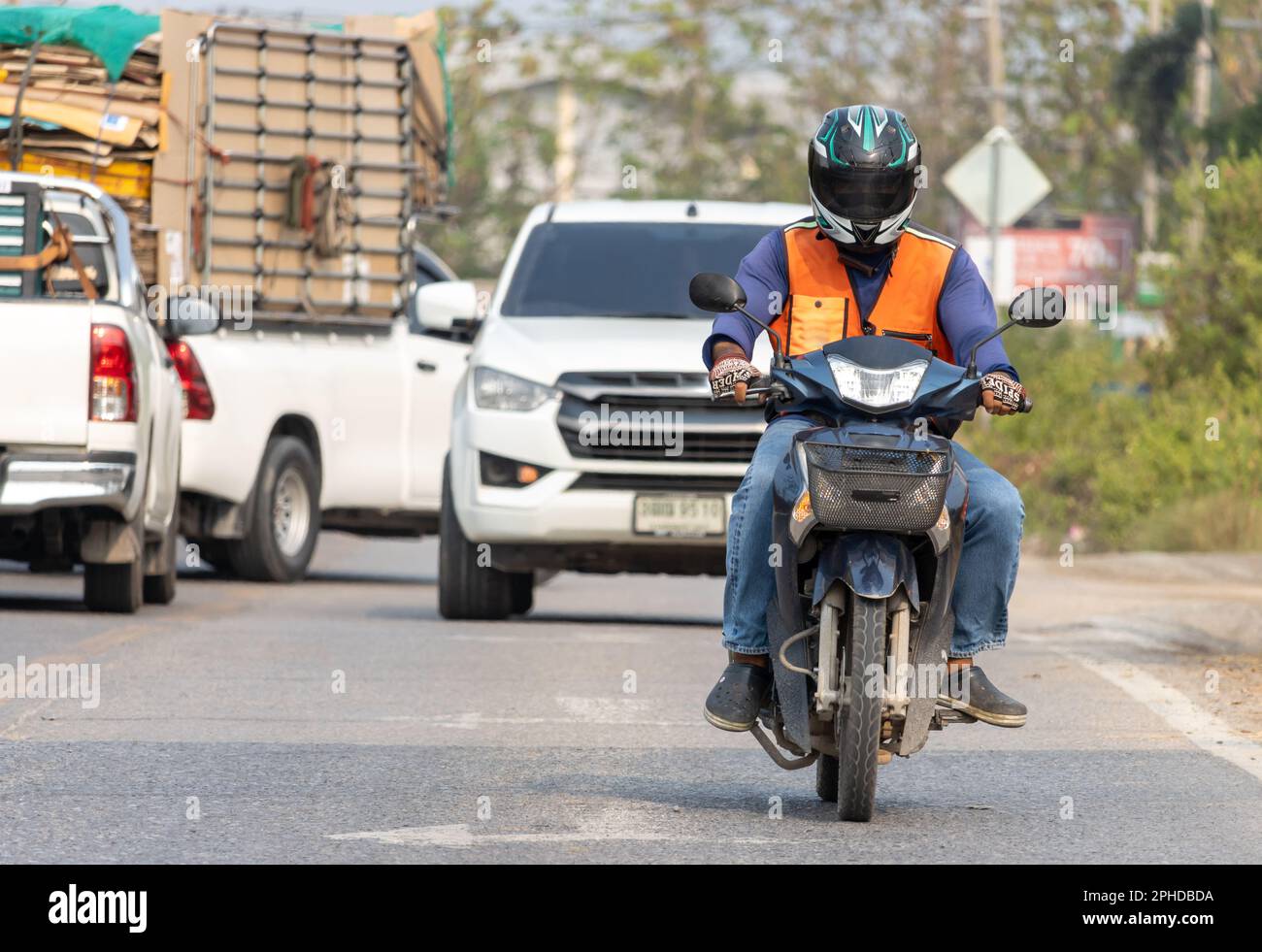 Front view of a man in an orange vest of a taxi driver riding a motorcycle, Bangkok, Thailand Stock Photo