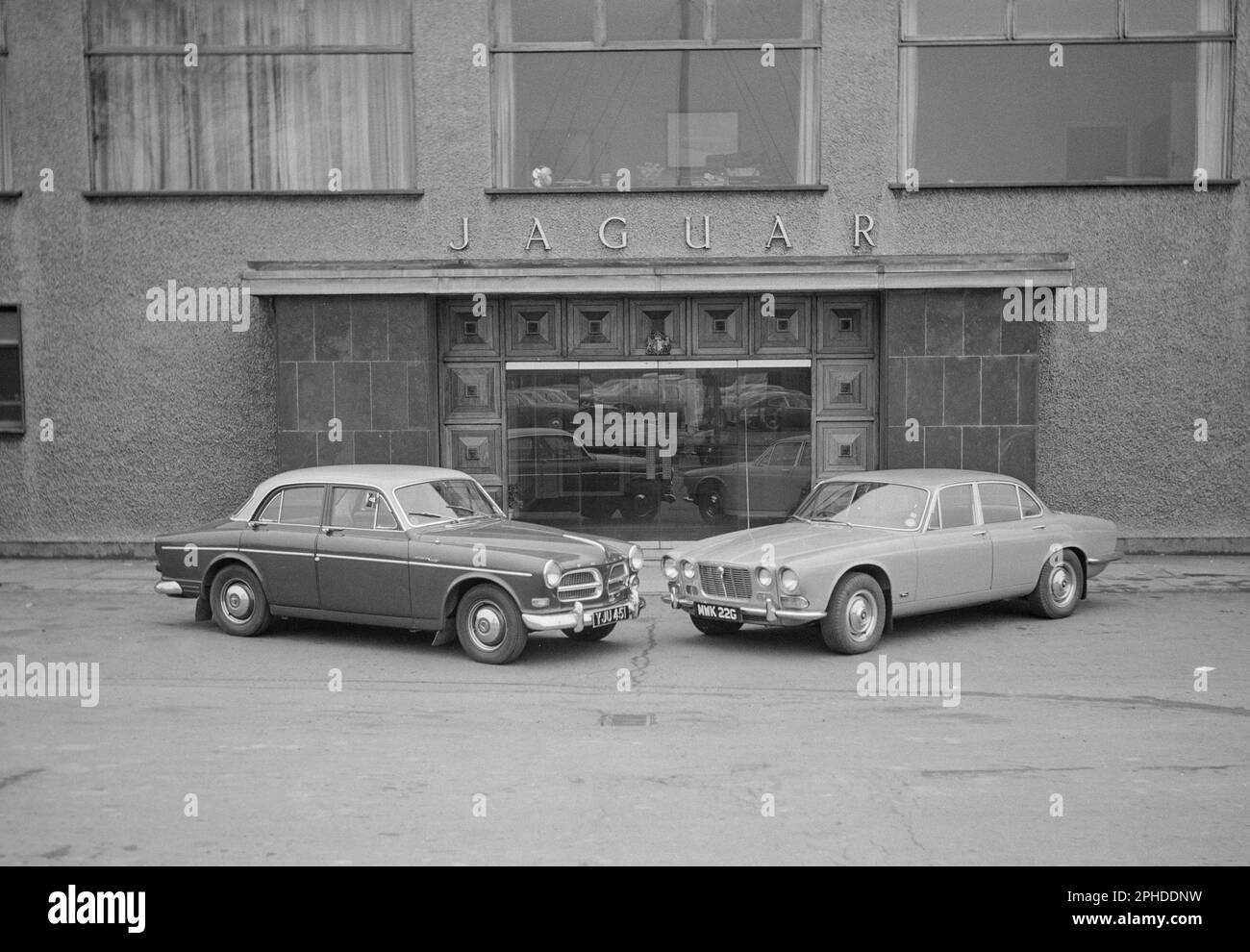 A 1968 photograph showing a Jaguar XJS 4.2, MWK 22G, used as a press car by Jaguar. Also a Volvo 122 Amazon, YJU 451. In front of the Jaguar Offices. Stock Photo