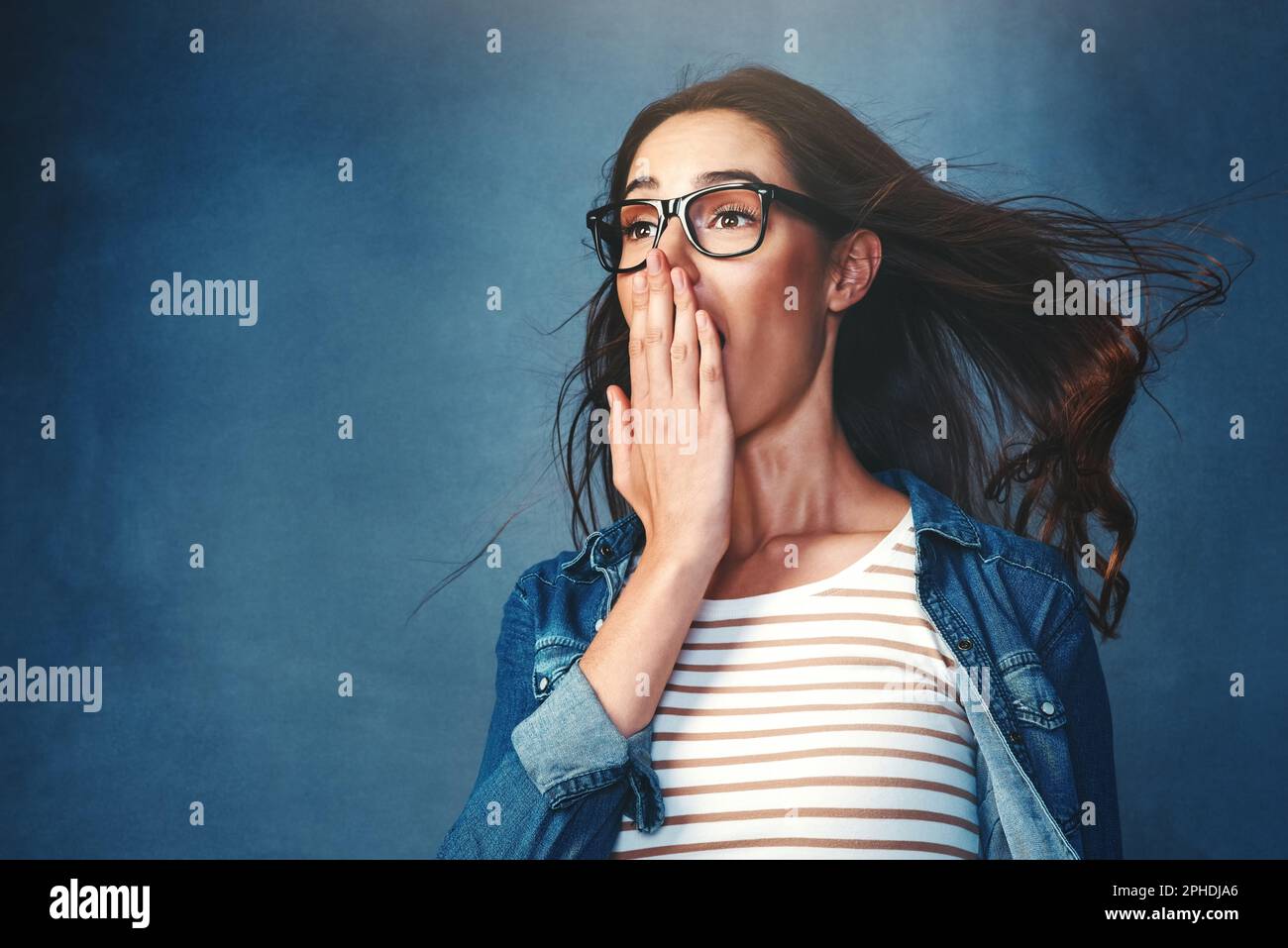 Now thats epic. Studio shot of a young woman with air being blown in her  face against a blue background Stock Photo - Alamy