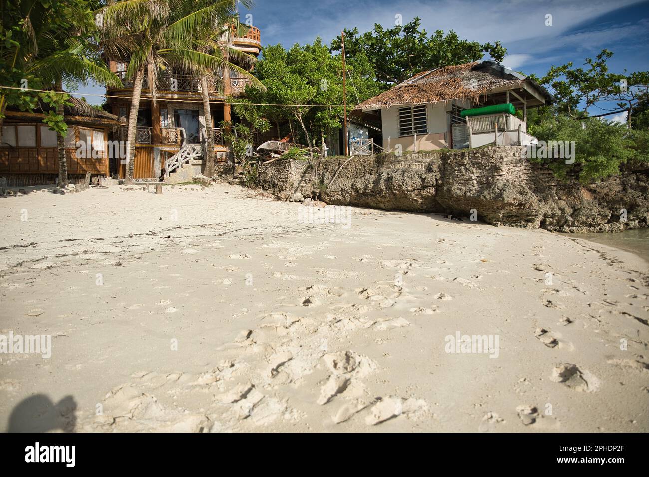 Dreamlike idyllic beach Siquijor in the Philippines with trees, cliffs and huts on the beach. Stock Photo