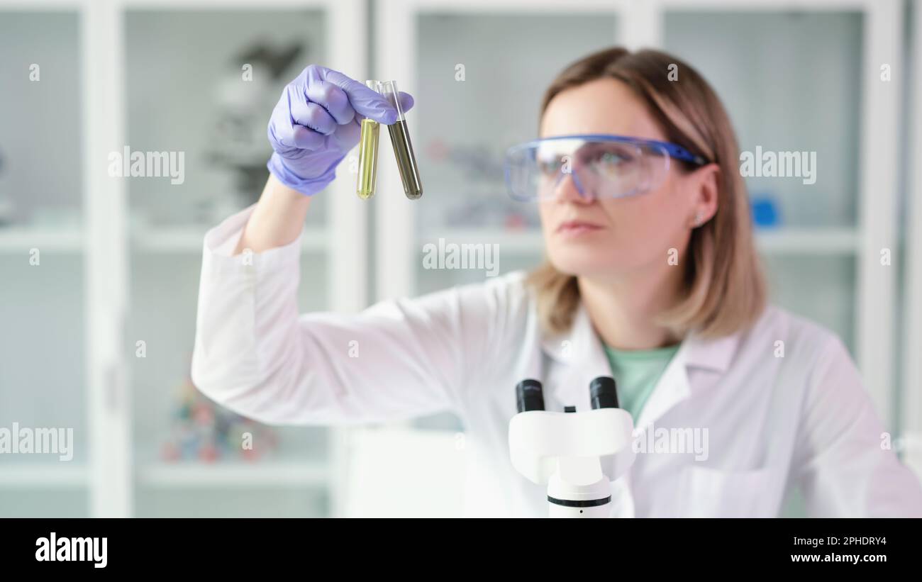Lab Fuelchemist Woman scientist chemist comparing test tubes with oil and contaminated ...