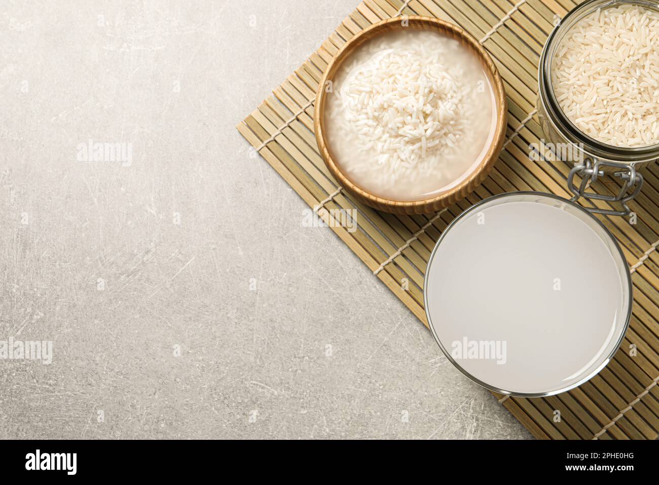 Flat lay composition with rice water on light grey table. Space for ...