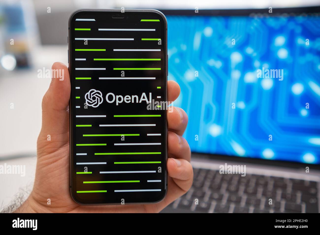 OpenAI logo of neural network on the screen of smartphone in mans hand and laptop with neuronet on the splash screen on the background. Artificial intelligence concept, March 2023, Prague, Czech Republic. Stock Photo