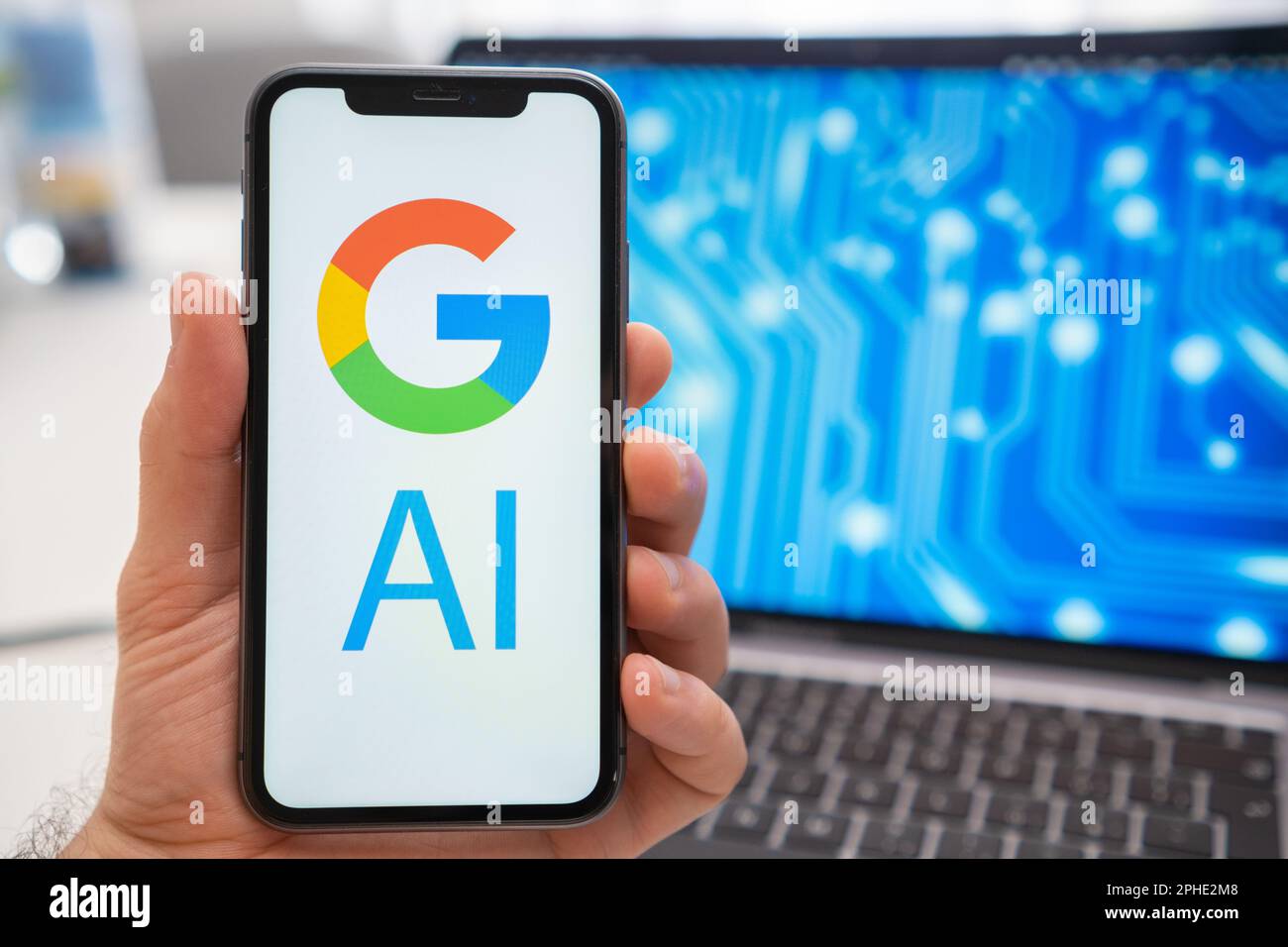 Google AI logo of neural network on the screen of smartphone in mans hand and laptop with neuronet on the splash screen on the background. Artificial intelligence concept.  Stock Photo
