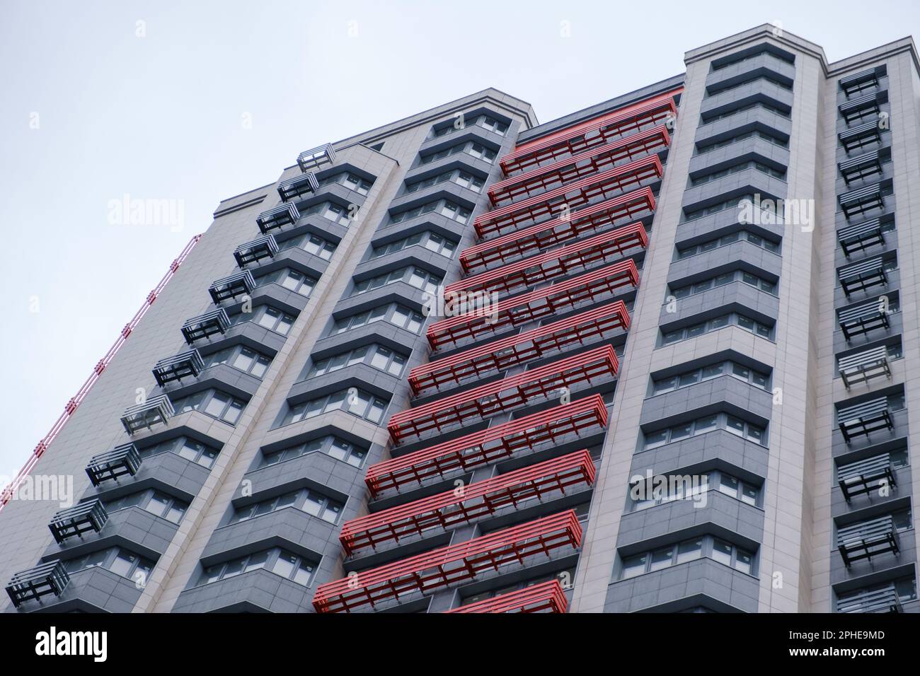 High-rise apartment building with balconies. Modern high-rise building with balconies, set against clear sky. Shot from a low angle, looking up towards the top of the building. Stock Photo
