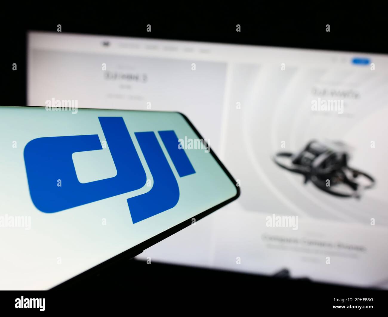 Smartphone with logo of drone company SZ DJI Technology Co. Ltd. on screen in front of business website. Focus on center-left of phone display. Stock Photo