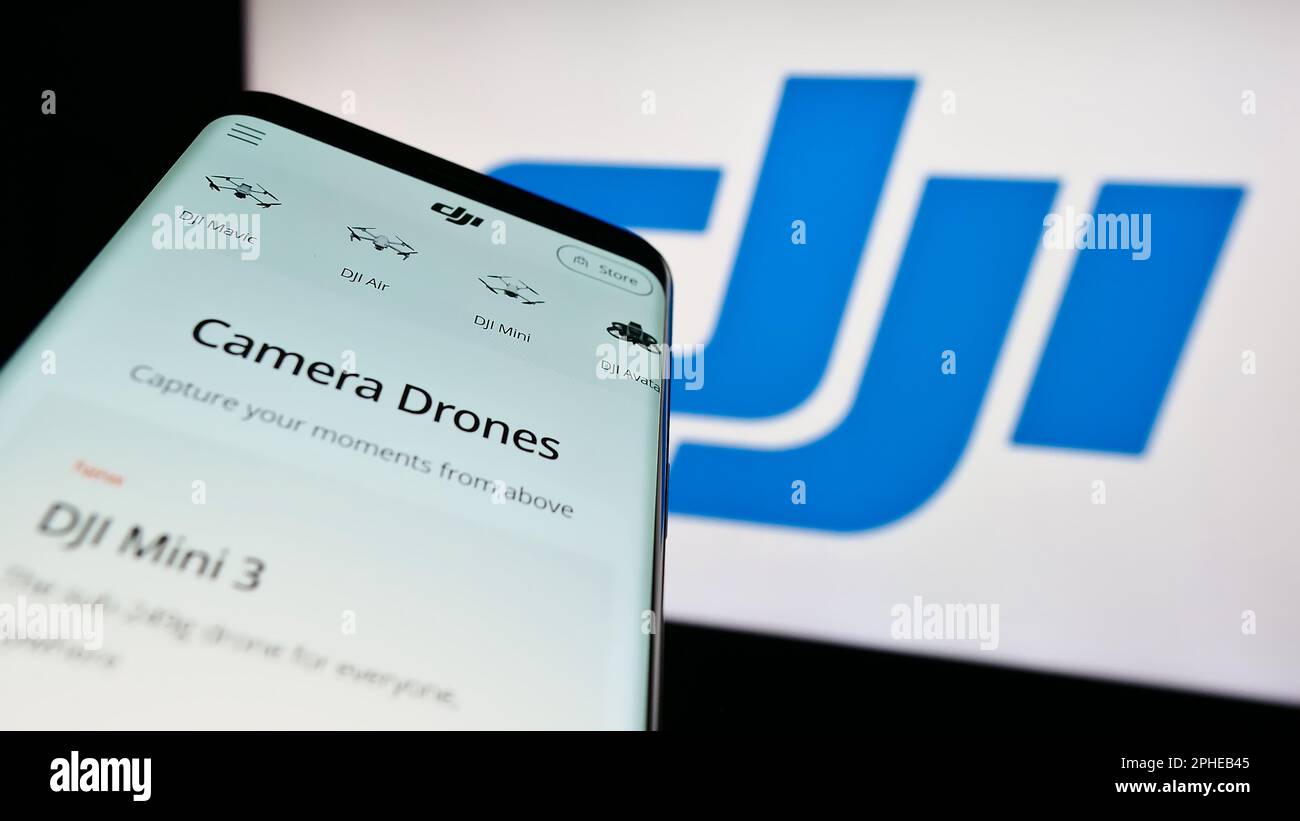 Mobile phone with webpage of drone company SZ DJI Technology Co. Ltd. on screen in front of business logo. Focus on top-left of phone display. Stock Photo