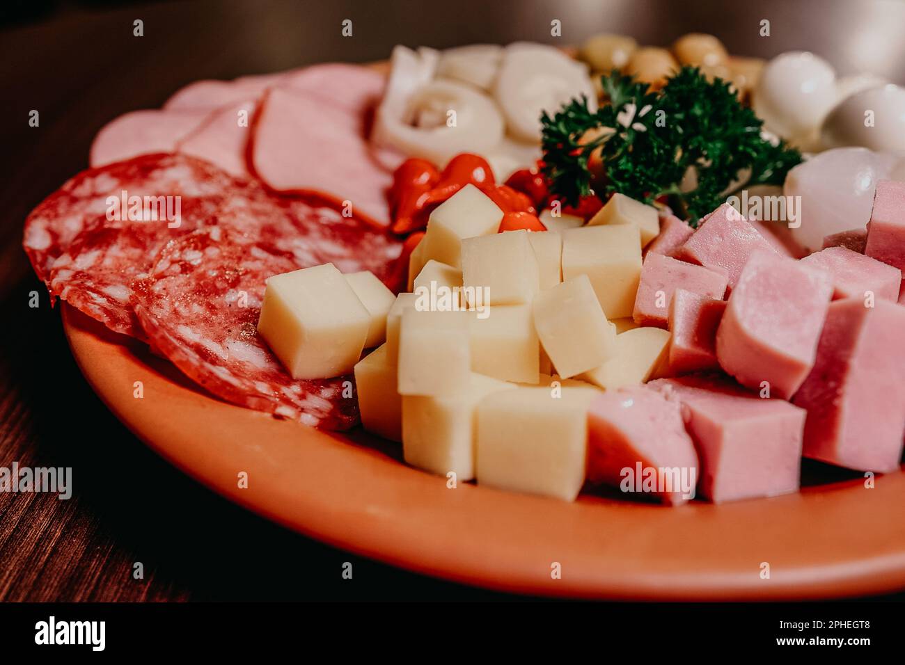 An assortment of various meats and cheeses arranged neatly on a plate, ready for cooking Stock Photo