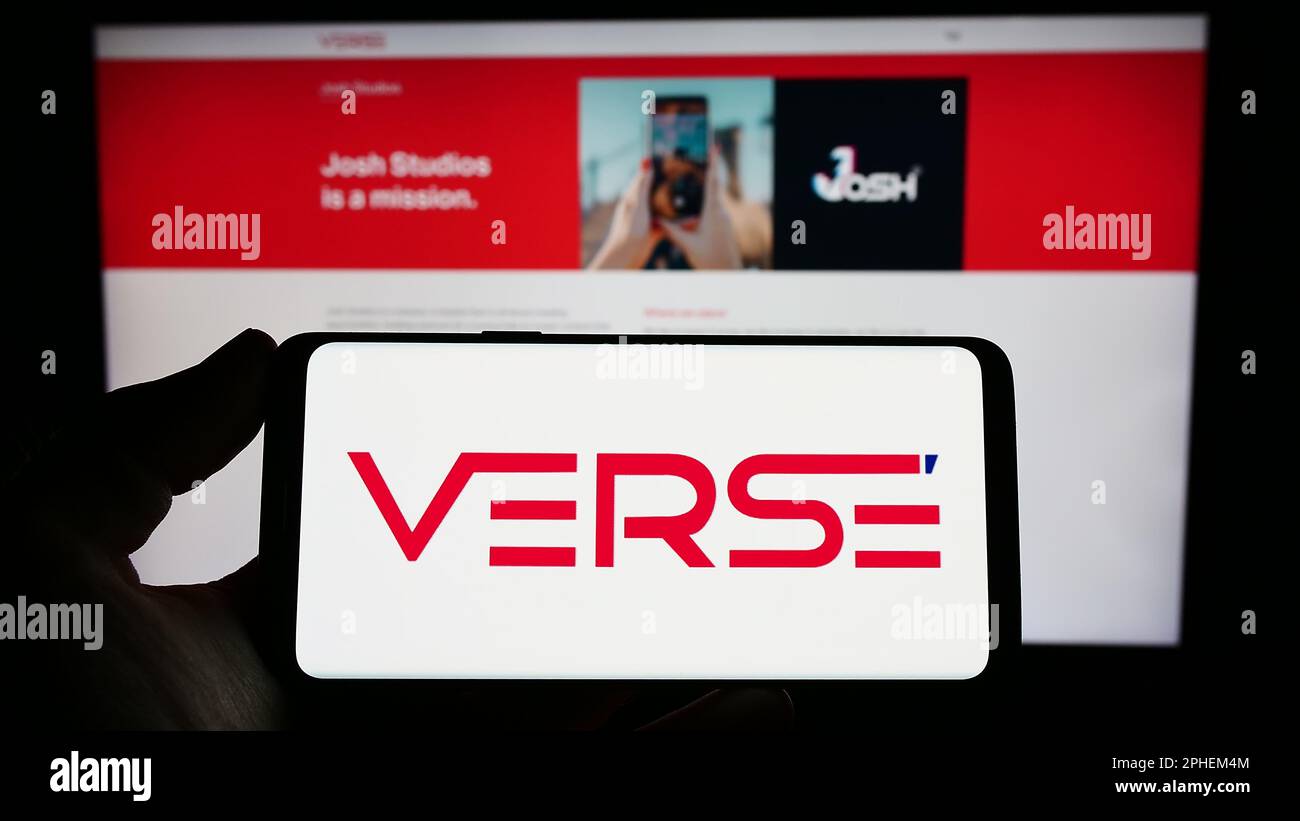 Person holding smartphone with logo of Indian company VerSe Innovation Pvt. Ltd. on screen in front of website. Focus on phone display. Stock Photo