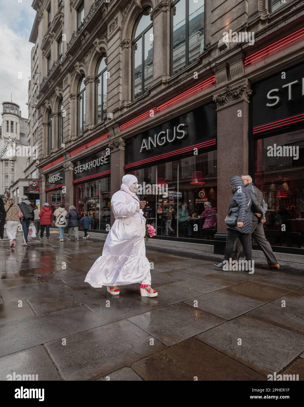 A ghost-like woman balloon-seller makes her way through central London. Stock Photo