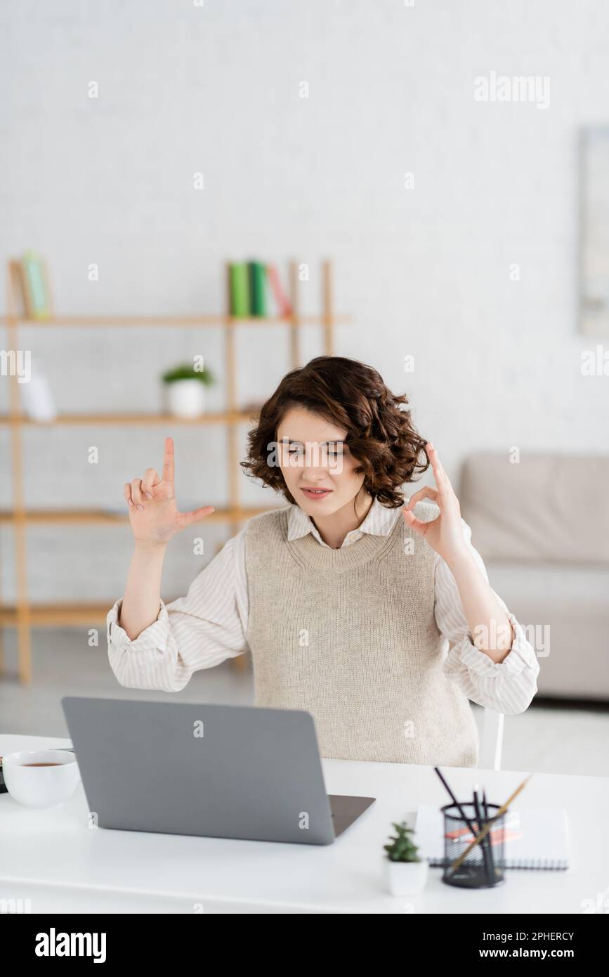 young sign language teacher showing alphabet letters with hands during