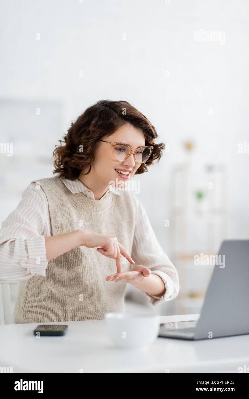 happy woman showing stand word while teaching sign language during online lesson on laptop,stock image Stock Photo