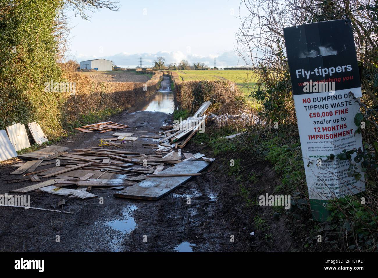 Fly tipped rubbish and building materials with a warning notice in a country lane, Bromley, UK Stock Photo