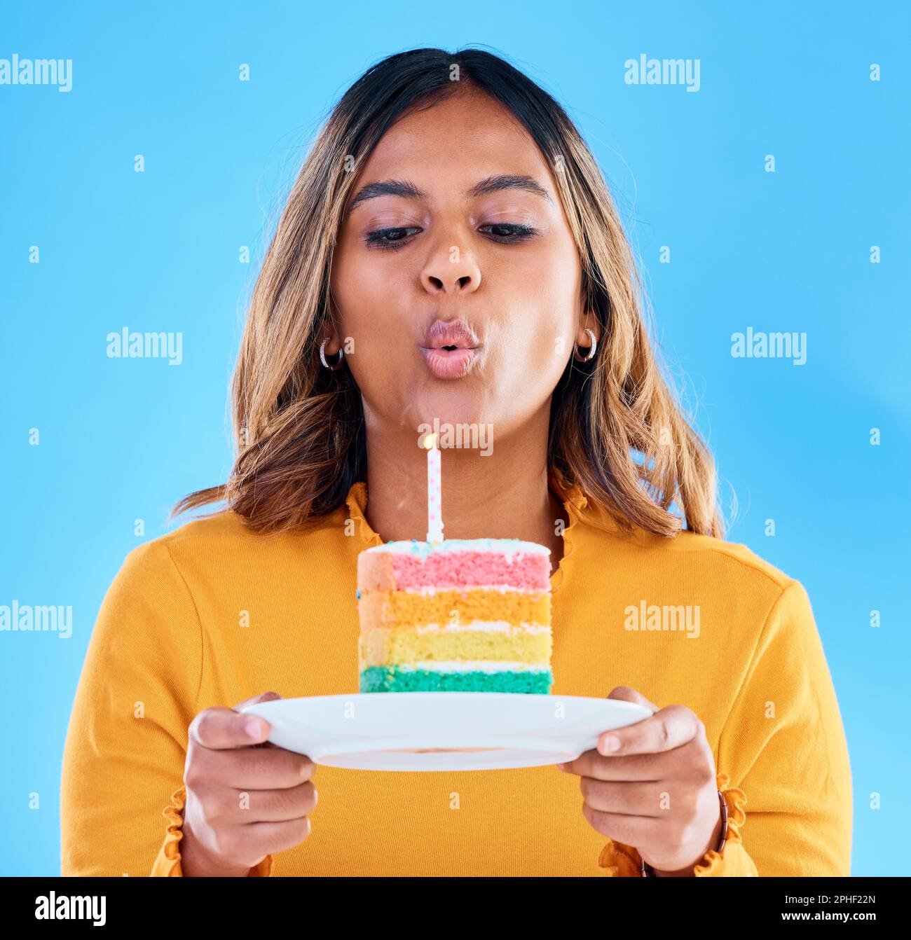 Birthday cake, candle blowing and woman in a studio with celebration