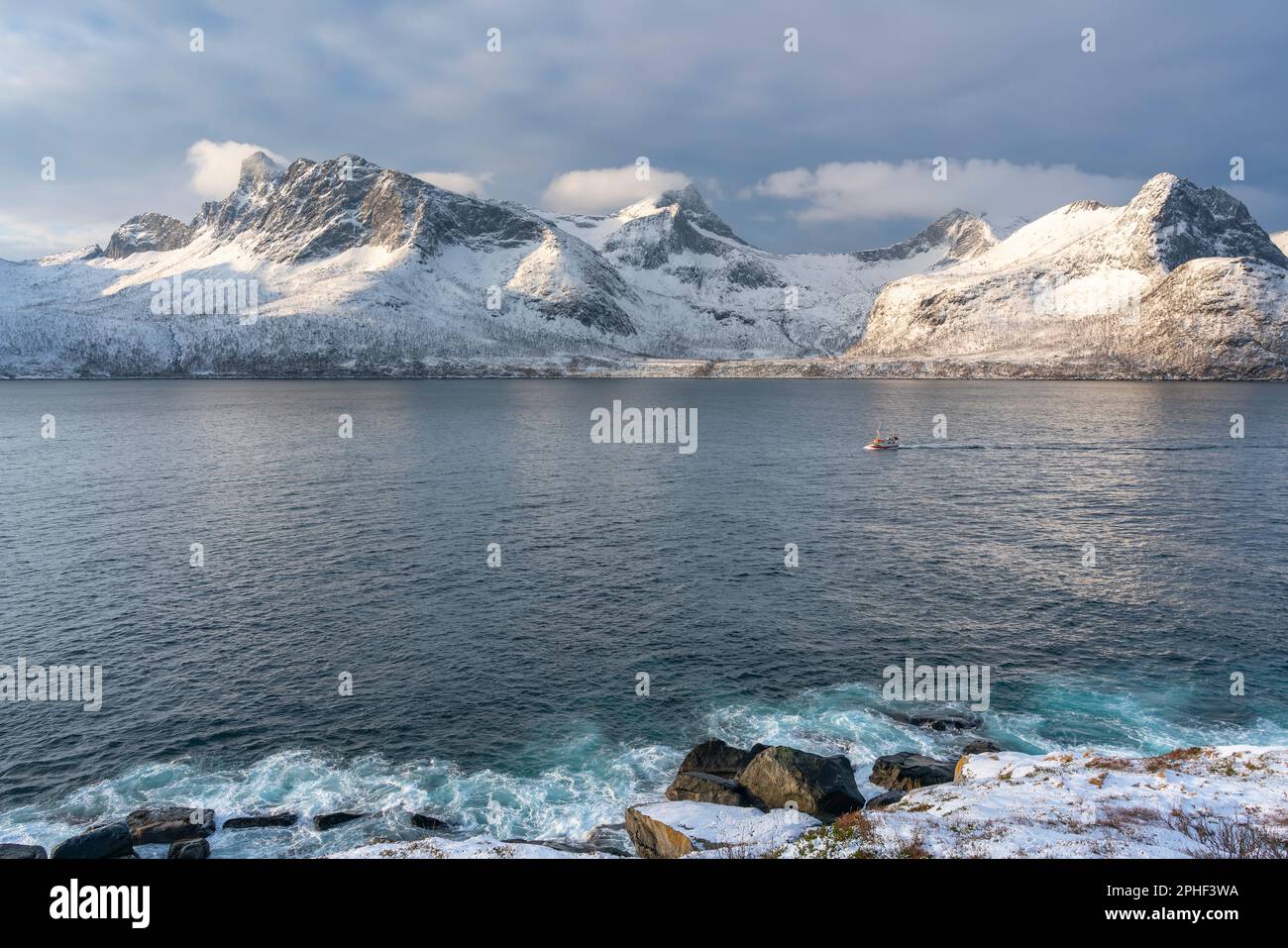 Fischer am Morgen, Schiff im Øyfjorden, mit den schneebedeckten Bergen von Senja, genannt Segla, Kongan und Skultran im Hintergrund. Norwegen Stock Photo