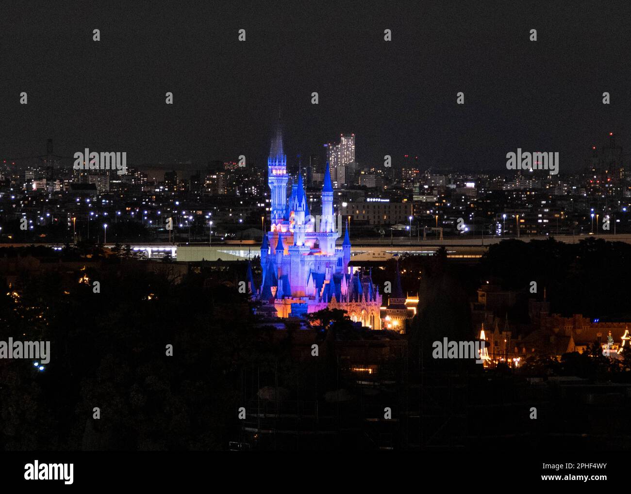 A night shot of Cinderella Castle all lighten up in Tokyo Disneyland with Tokyo City in the background. Stock Photo
