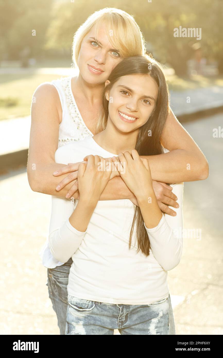 Young, caring mom hugging teen daughter, while posing to camera Stock