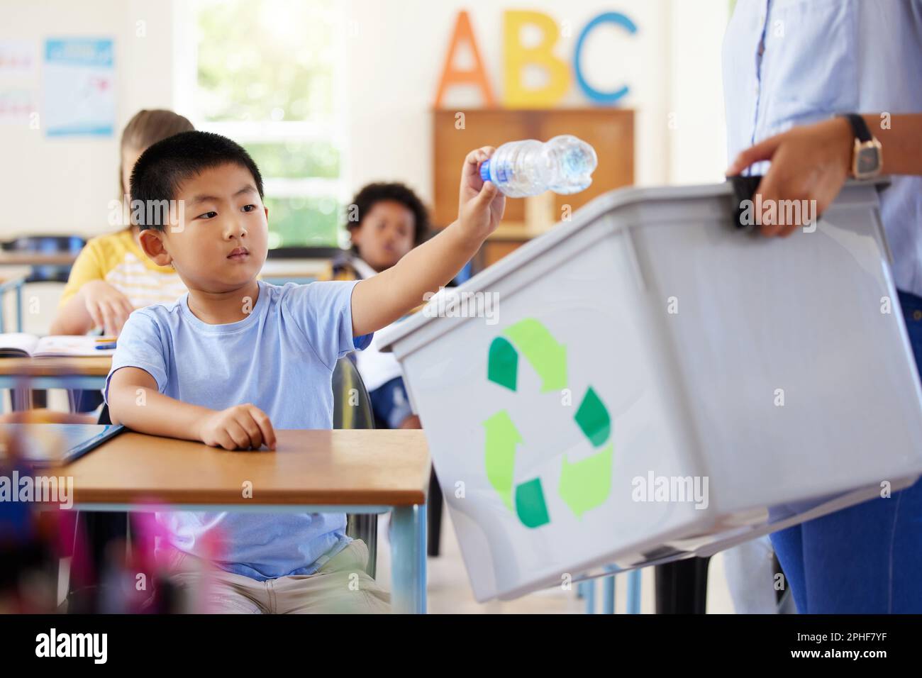 Teacher, recycle bin and kid in classroom throwing trash for cleaning, climate change or eco