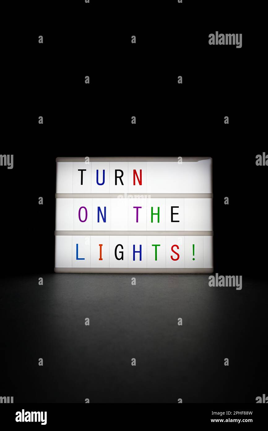 Bright shining "Turn on the lights" neon sign in the dark on black back