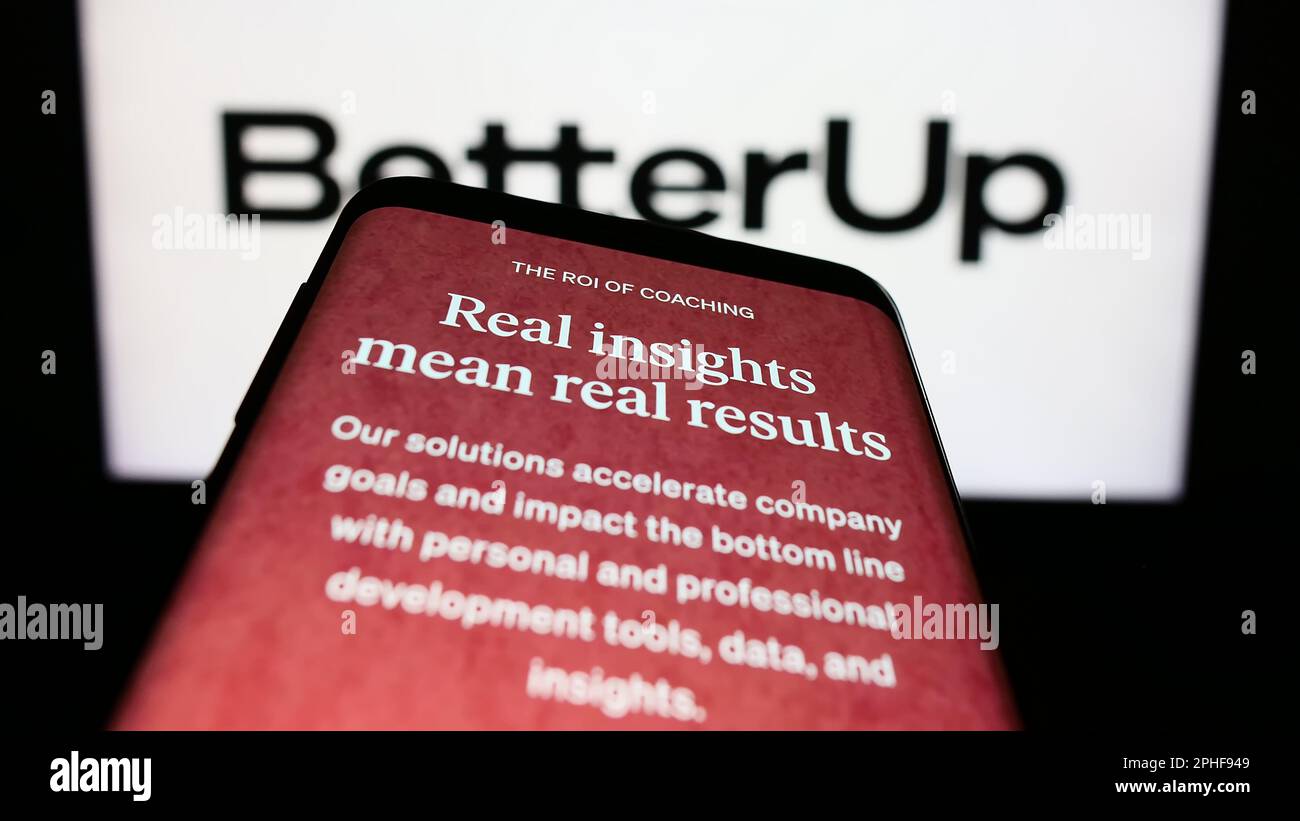 Mobile phone with website of US coaching company BetterUp on screen in front of business logo. Focus on top-left of phone display. Stock Photo