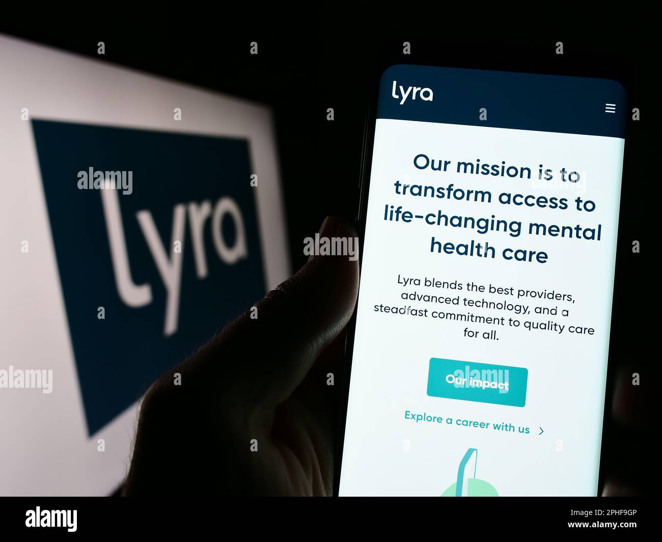 Person holding smartphone with webpage of US mental health company Lyra Health Inc. on screen in front of logo. Focus on center of phone display. Stock Photo