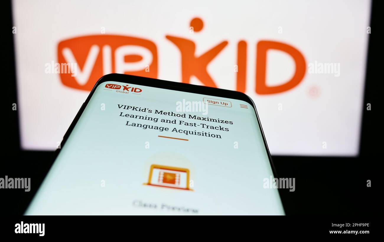 Mobile phone with webpage of e-learning company VIPKid on screen in front of business logo. Focus on top-left of phone display. Stock Photo
