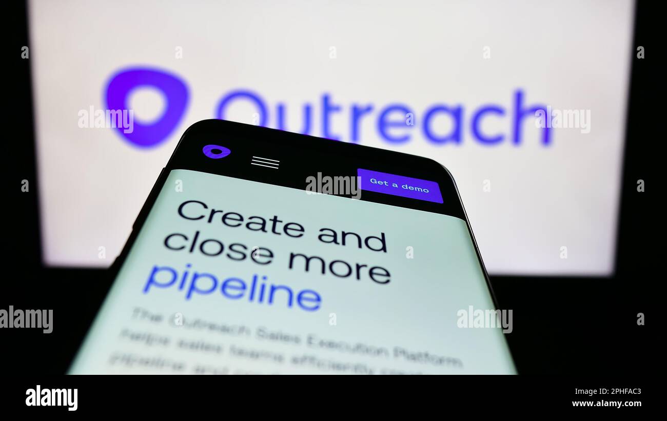 Smartphone with website of US sales software company Outreach.io on screen in front of business logo. Focus on top-left of phone display. Stock Photo