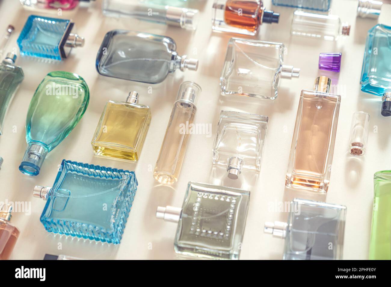 Perfumery, cosmetics and beauty industry background. A lot of transparent bottles of perfume and cologne and toilet water lie neatly on a beige backgr Stock Photo