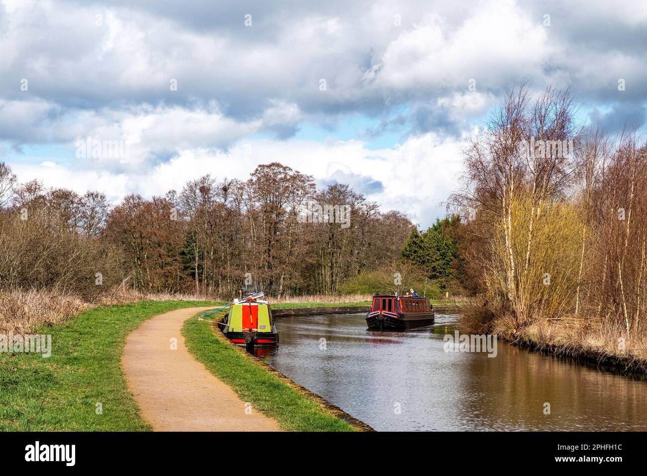 Narrow boats, one moored, on the Trent and Mersey canal in Cheshire UK Stock Photo
