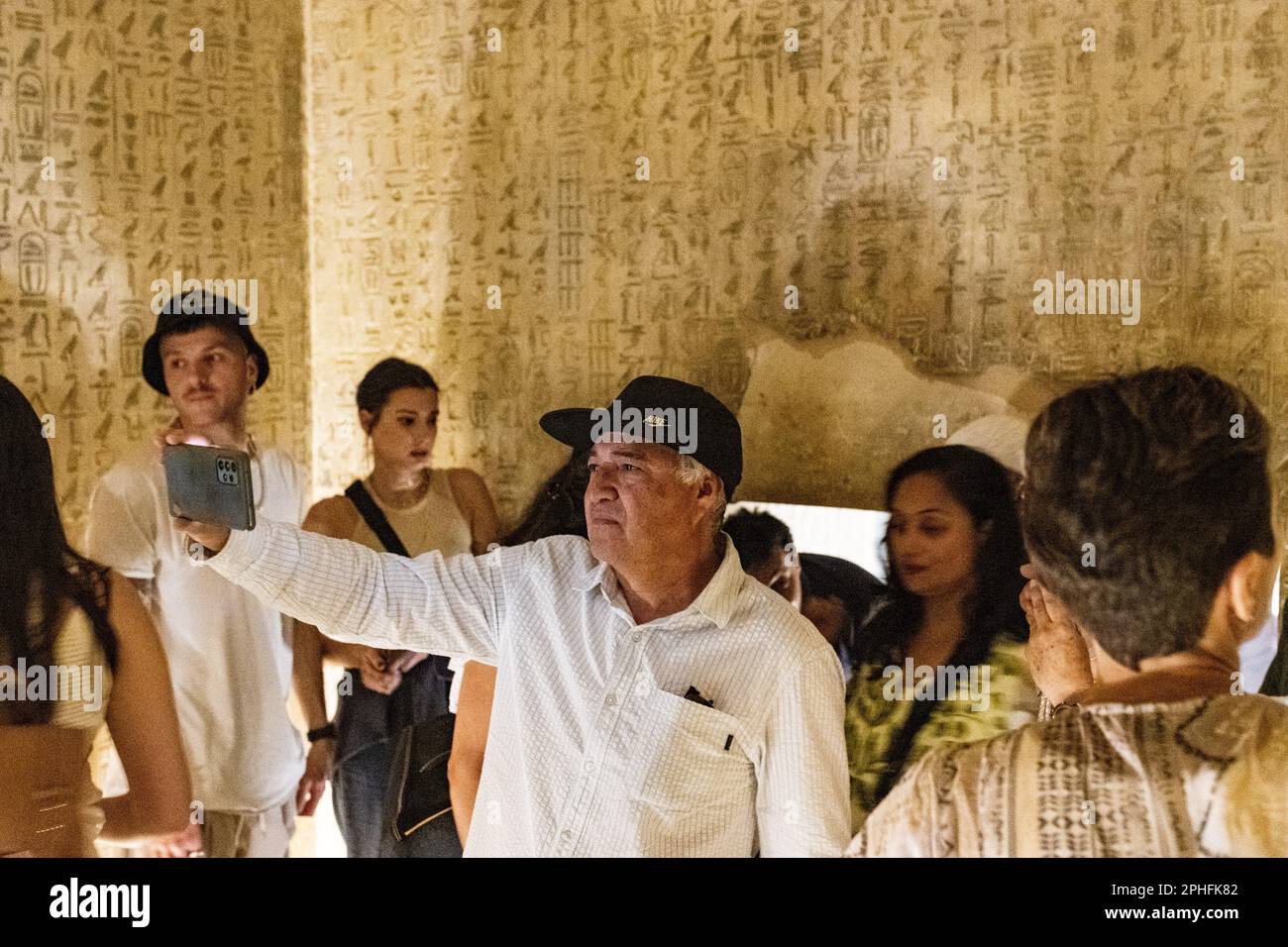 People / Tourists taking photos of the hieroglyphics in an underground burial chamber inside the Pyramid of Unas at Saqqara Necropolis in Giza, Egypt Stock Photo