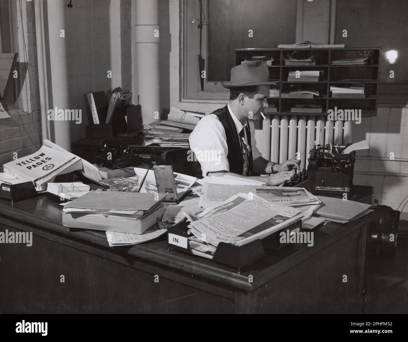 Man wearing a fedora and smoking a cigarette in an untidy office types a document, Washington, DC, circa 1946. (Photo by United States Information Agency Stock Photo