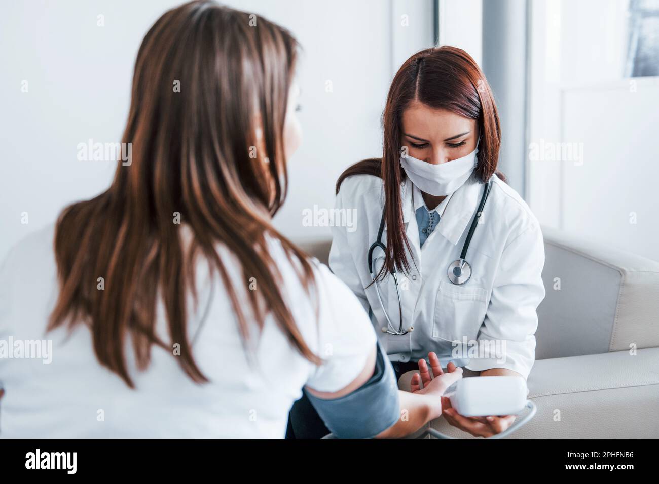 Measuring blood pressure. Young woman have a visit with female doctor ...