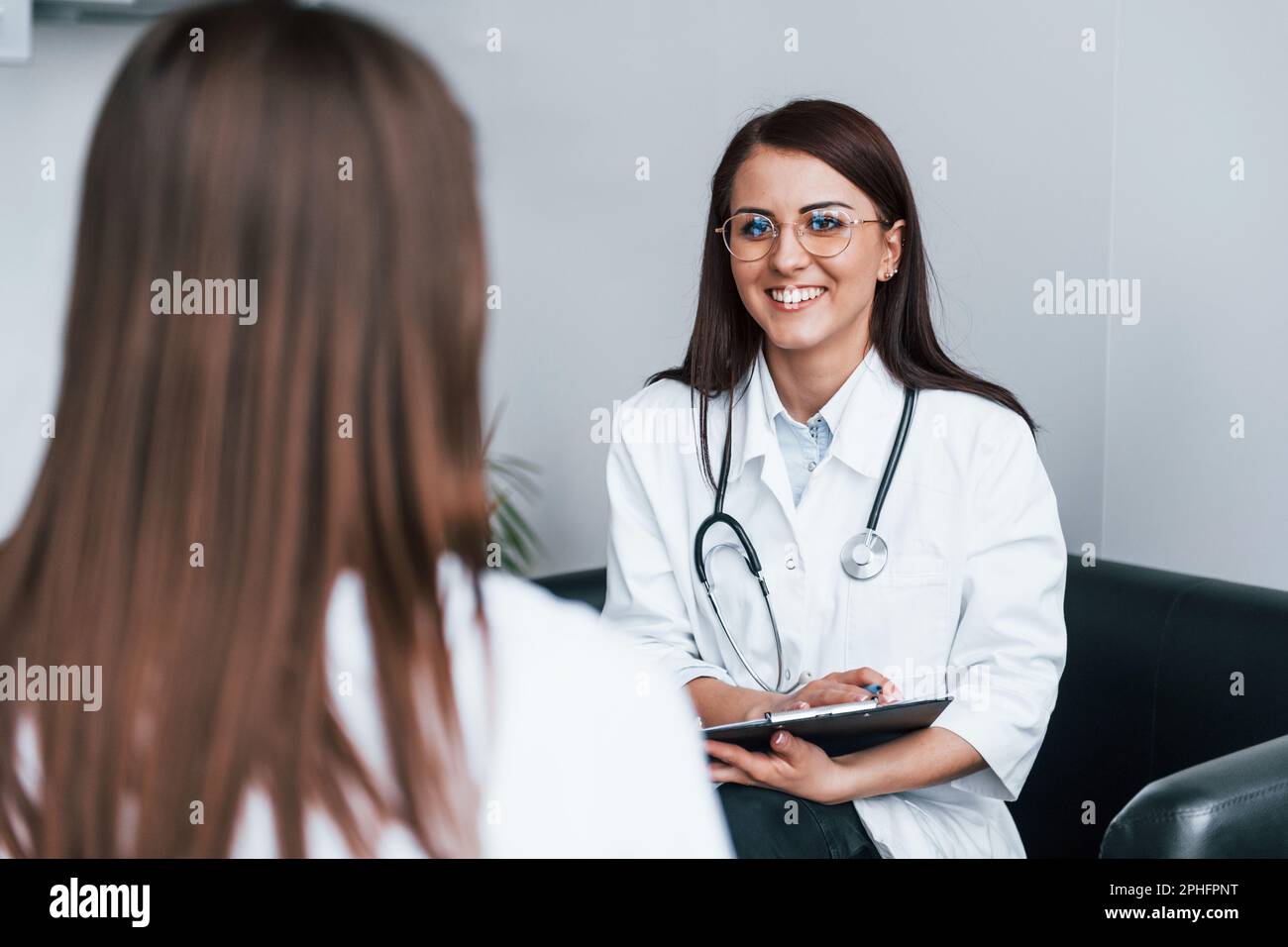 Sitting and talking. Young woman have a visit with female doctor in ...