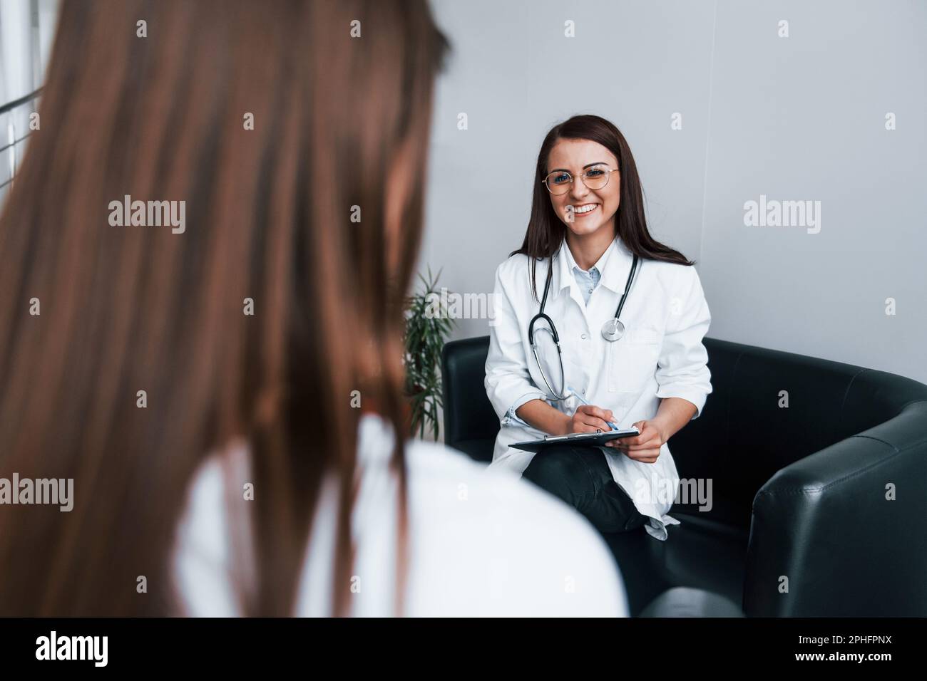 Sitting and talking. Young woman have a visit with female doctor in ...