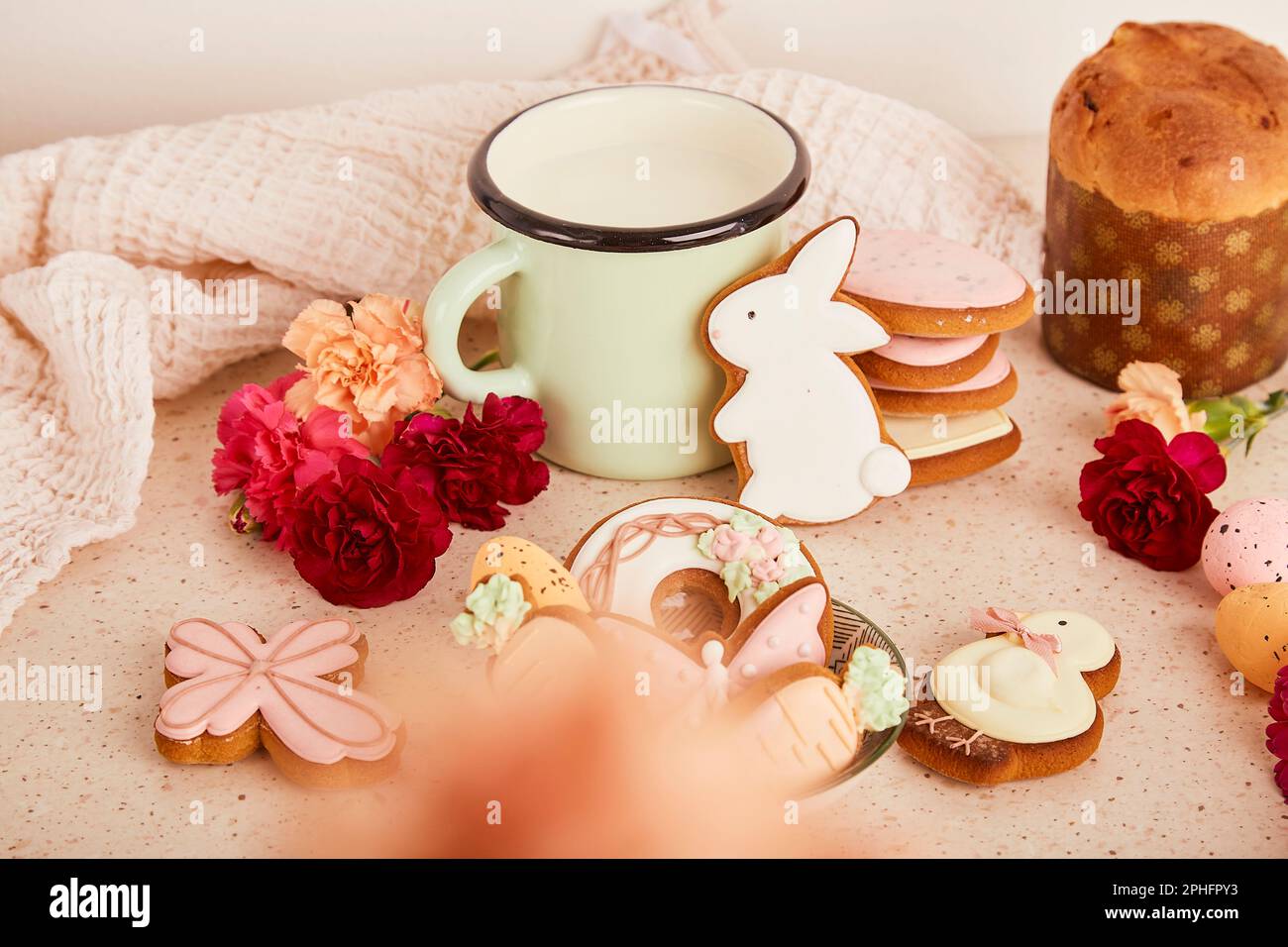 Aesthetic cozy Easter table with milk mug with glazed cookies, Cake and flowers. Springtime holiday floral background Stock Photo