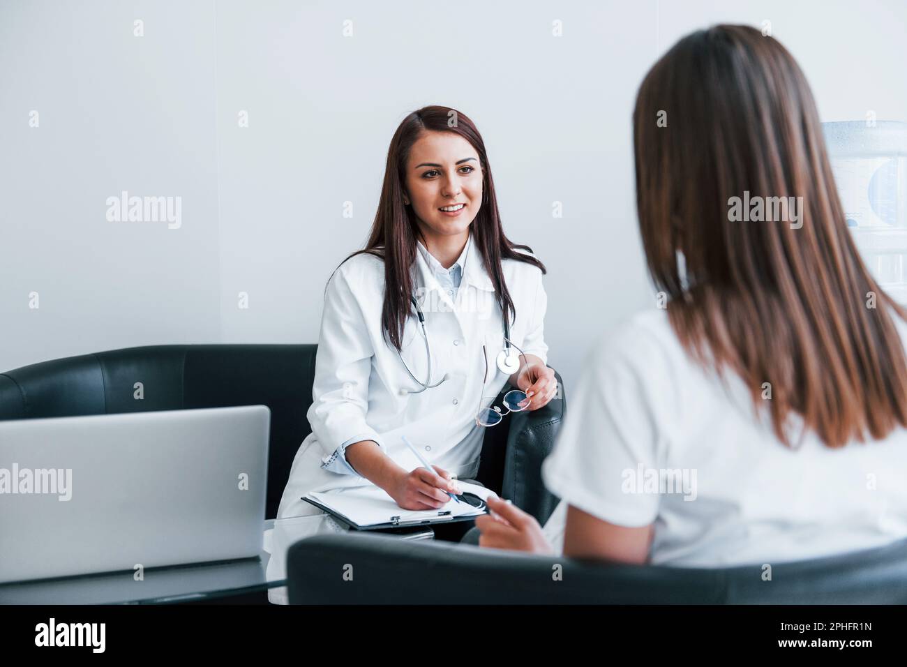 Sitting and talking. Young woman have a visit with female doctor in ...