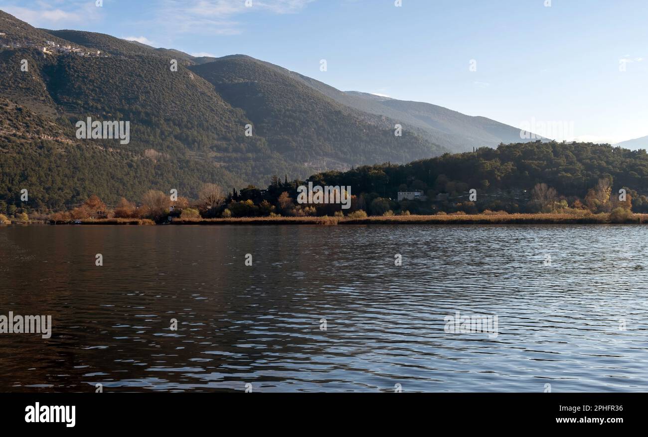 Greece, Pamvotis Lake, Ioannina city, Epirus. Destination Giannena, view of dark calm water, nisaki, nature, afternoon blue sky background. Stock Photo