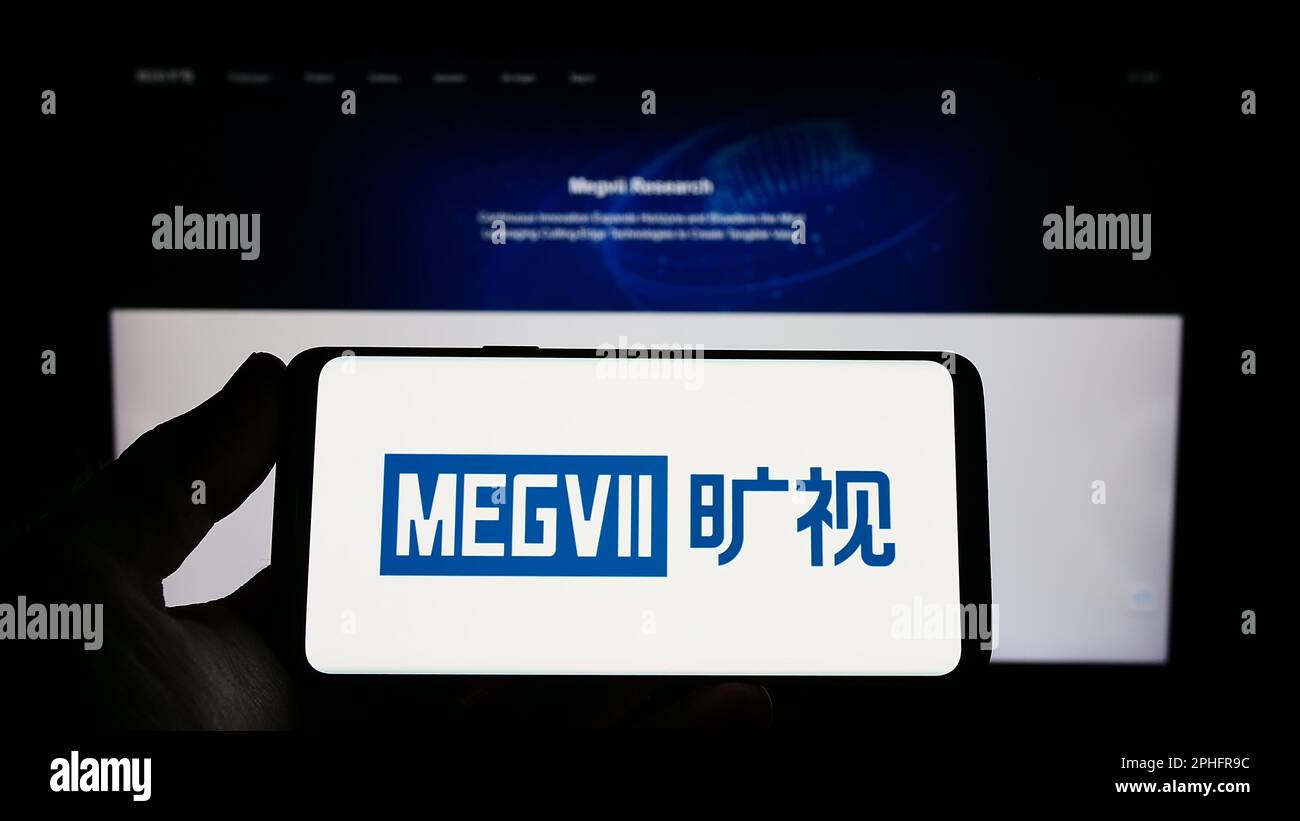 Person holding smartphone with logo of Chinese company Megvii Technology Limited on screen in front of website. Focus on phone display. Stock Photo