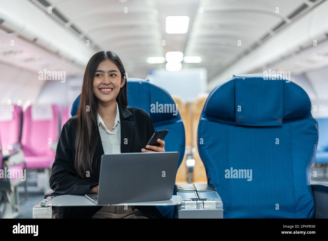 transport, tourism and technology concept of business woman with smartphone and laptop traveling by plane Stock Photo