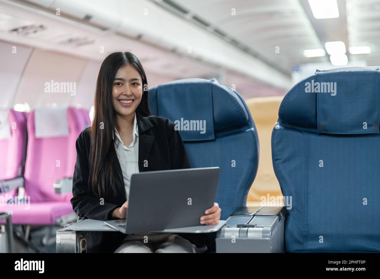 Female passenger sitting on plane while working on laptop computer with simulated space using on board wireless connection Stock Photo