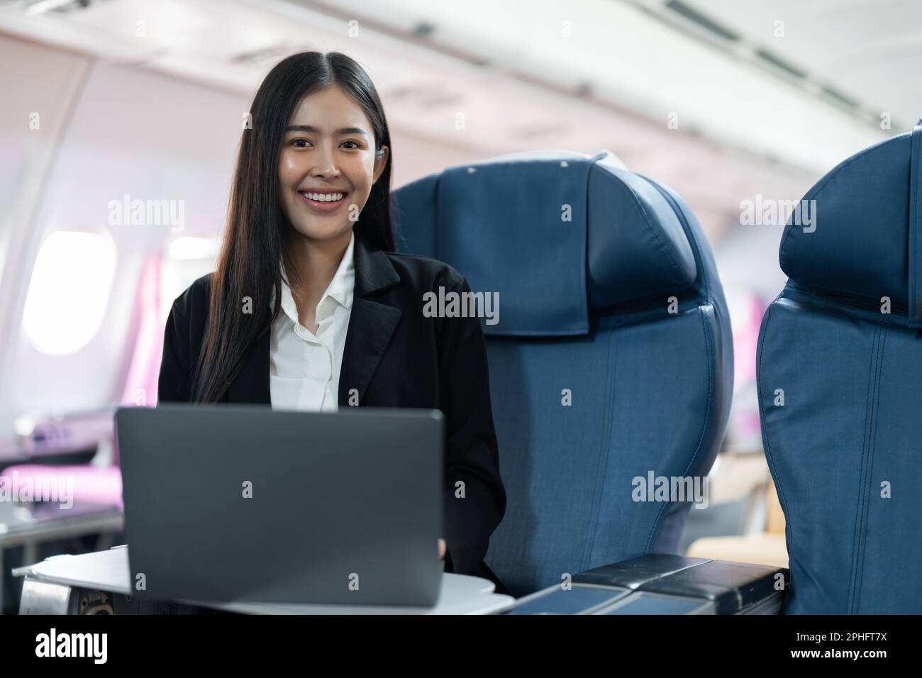 Female passenger sitting on plane while working on laptop computer with simulated space using on board wireless connection Stock Photo