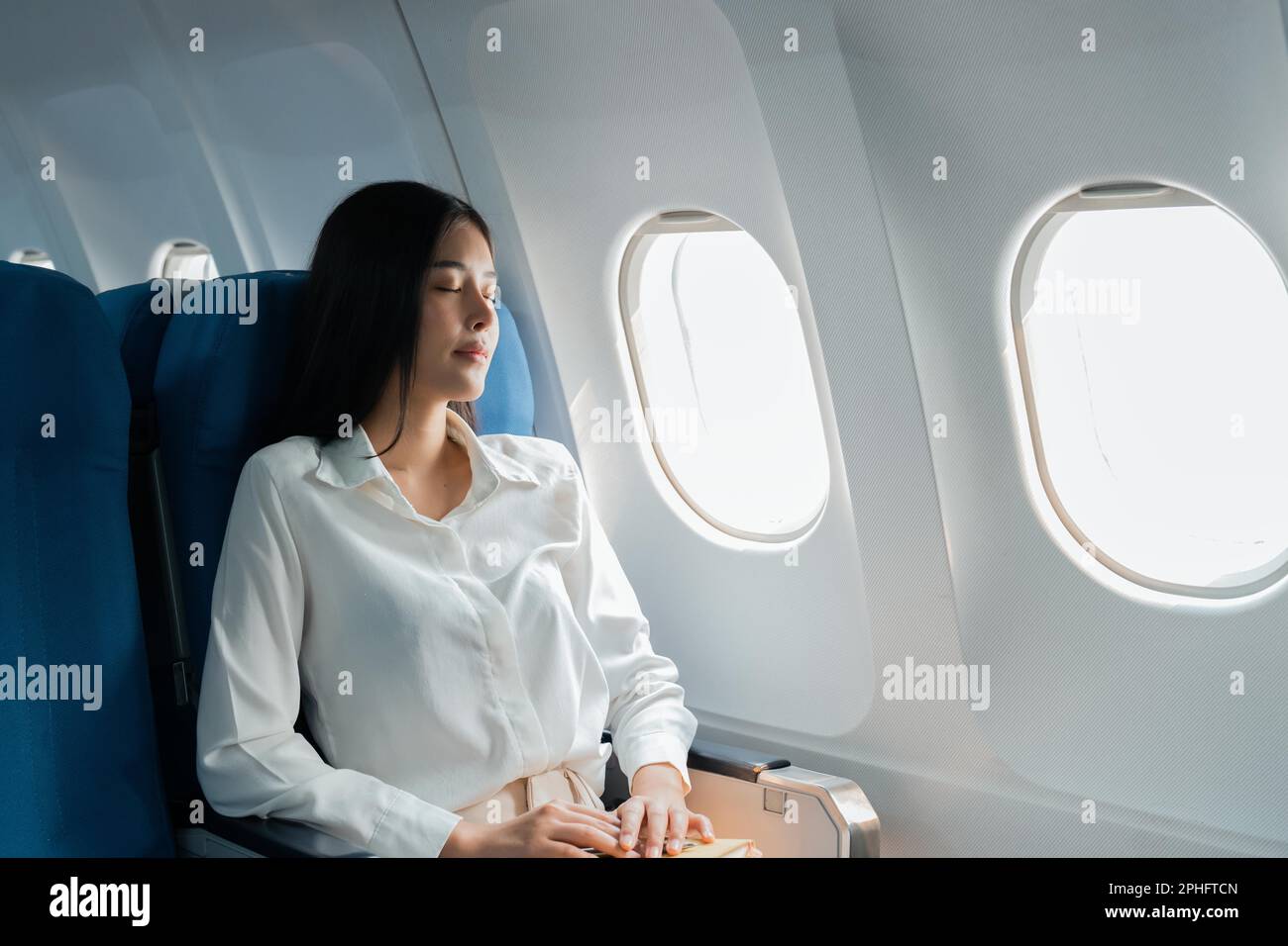 A female passenger traveling by plane sleeping on cushion airplane Stock Photo