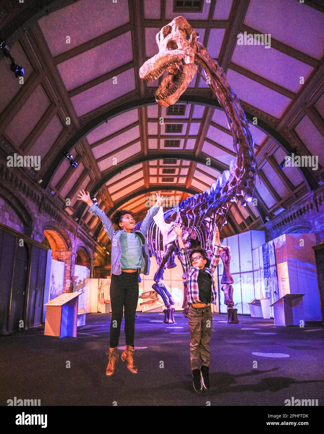 London, UK. 28th Mar, 2023. (EMBARGOED until Wed 29th, 19.30 BST, child models are both released by the museum) Eva (10) and Eliza (7) have fun exploring the Titanosaur exhibit. The largest known creature to have ever walked our planet, the Titanosaur (Titanosaur Patagotitan Mayorum), is displayed for the first time ever in Europe. On display until January 7 at the Natural History Museum in South Kensington. Credit: Imageplotter/Alamy Live News Stock Photo