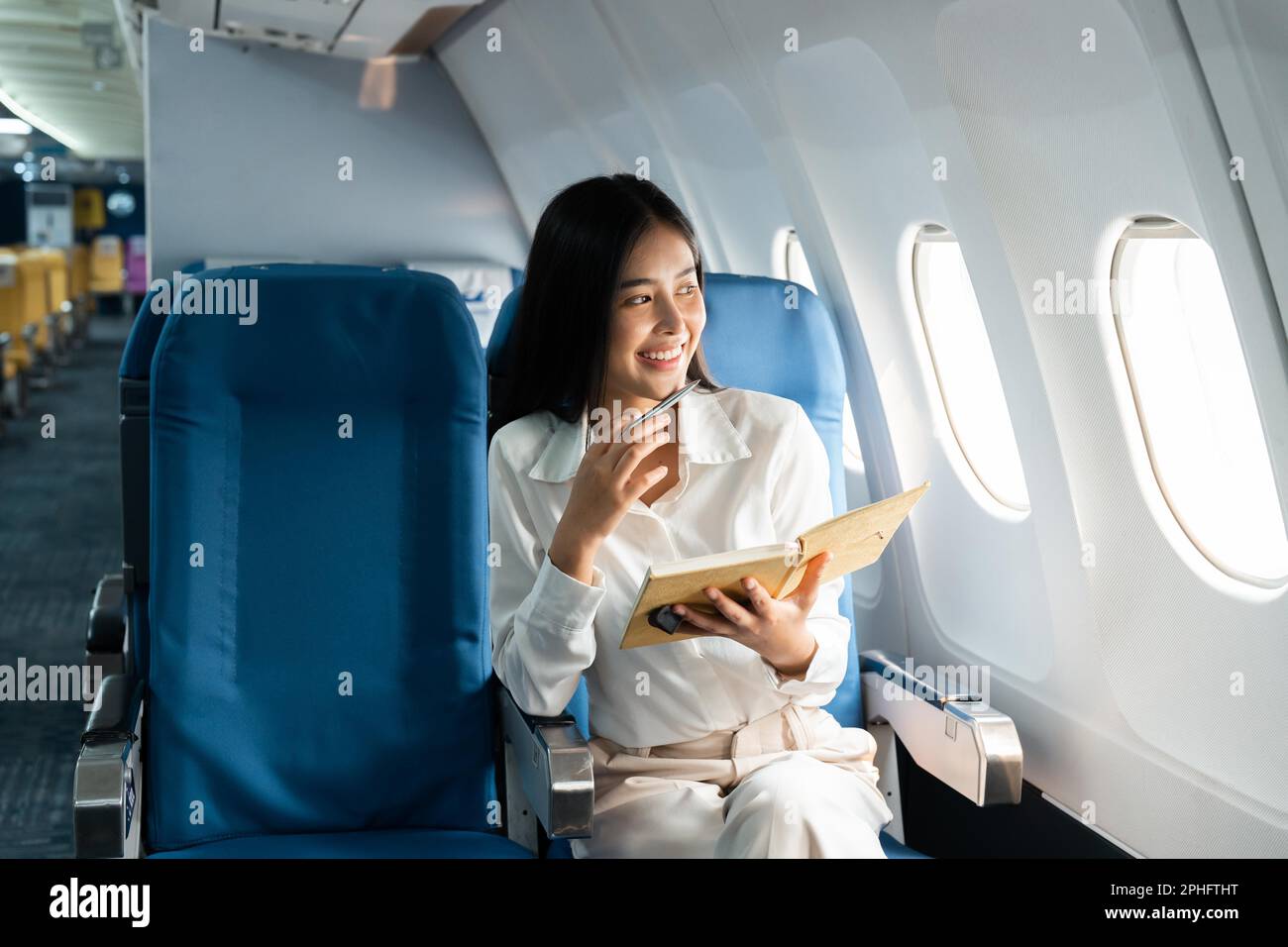 Asian female thinking about work in airplane concept Business traveling and technology concept Stock Photo