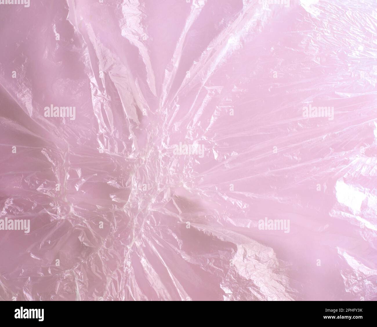 Close-up image of transparent melted plastic cellophane film on pink background. Abstract pattern of fused textured polyethylene. Horizontal format. Stock Photo
