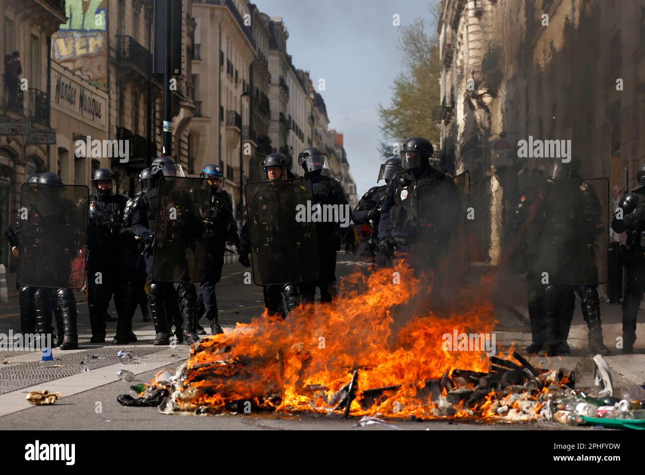 Riot police officers stand behind a street fire during a demonstration  Tuesday, March 28, 2023 in Nantes, western France. The fresh wave of  strikes and protests is the 10th time since January