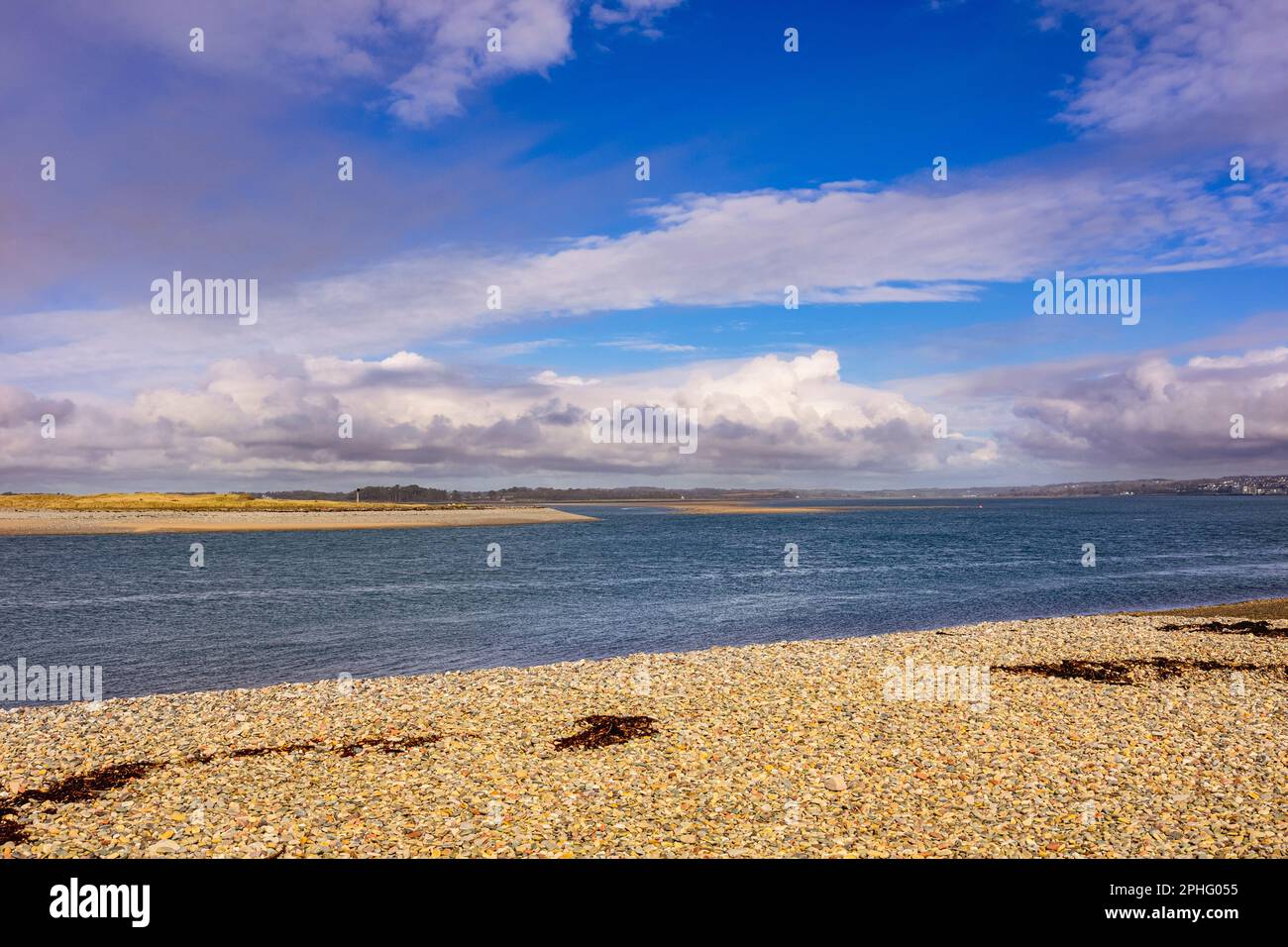 View from beach on mainland to Abermenai Point on Anglesey across the Menai Strait. Dinas Dinlle, Caernarfon, Gwynedd, north Wales, UK, Britain Stock Photo
