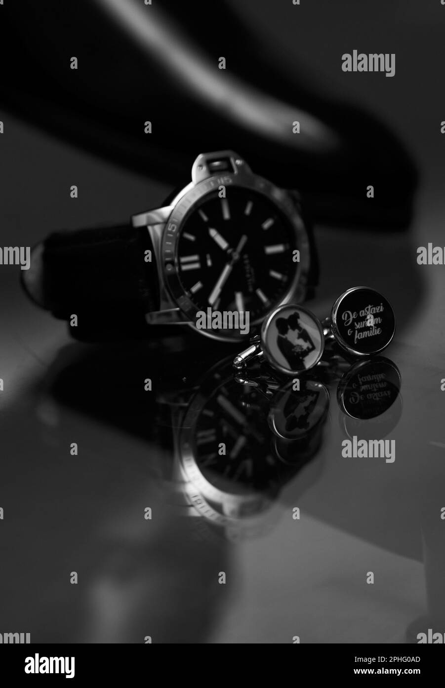 A vertical greyscale of a men's Hilfiger watch next to wedding