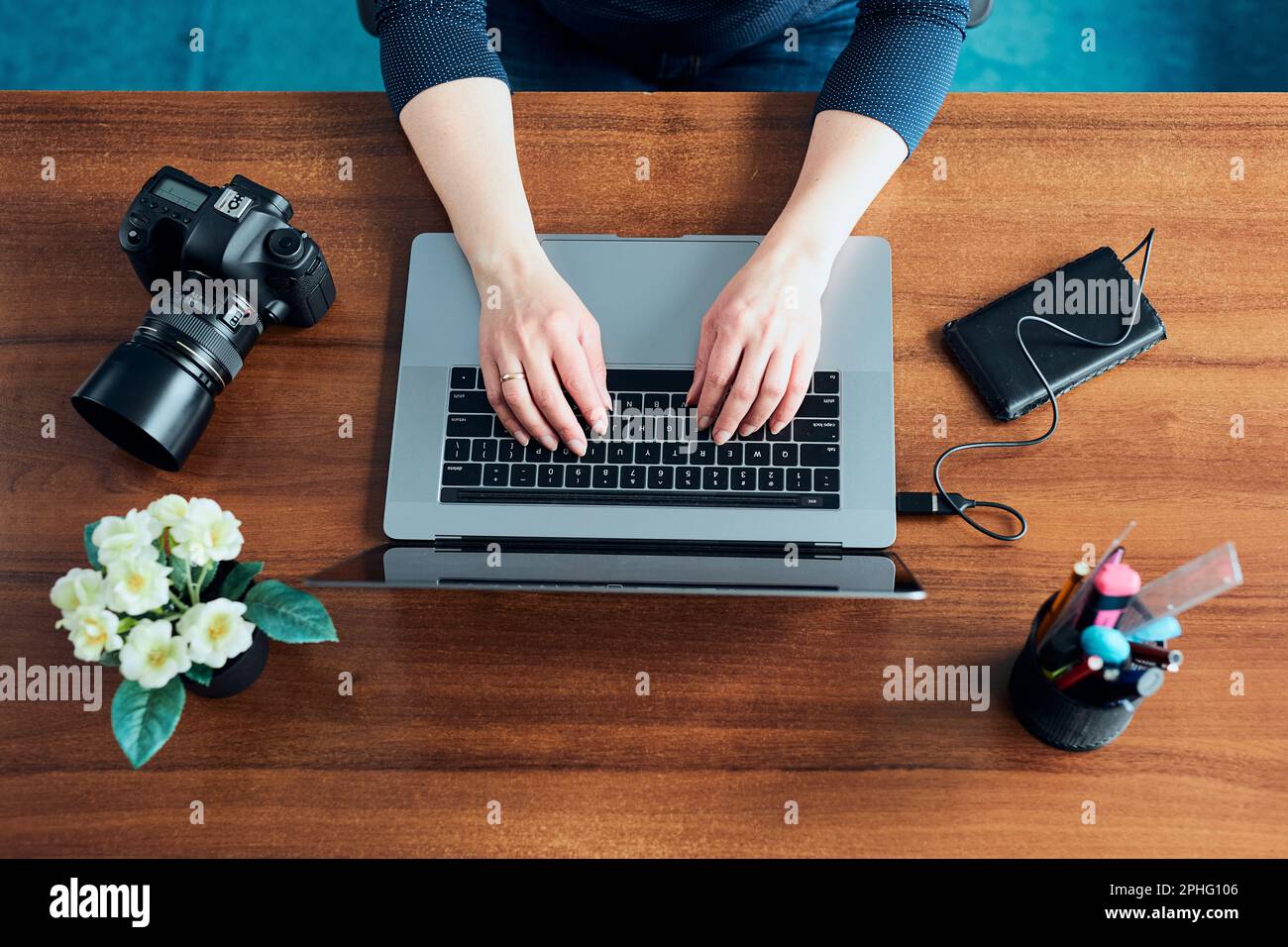 Female photographer working on photos on laptop and camera. Woman editing retouching browsing photos working as a freelancer sitting at desk Stock Photo