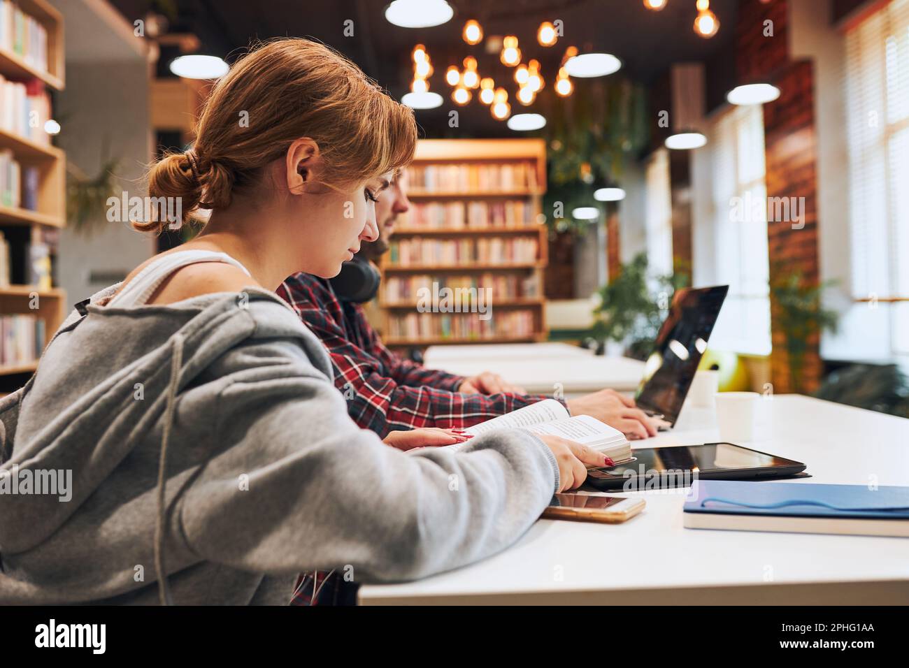 Students learning in university library. Young man preparing for test on laptop. Girl learning